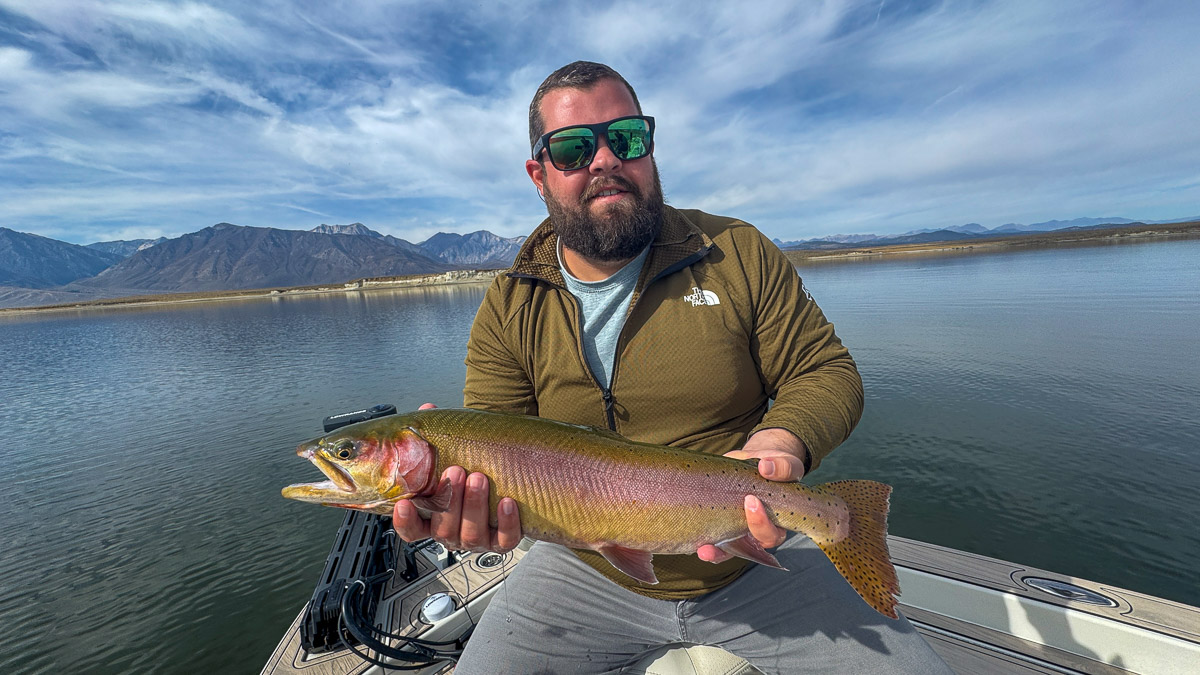 A fly fishermen holding a large cutthroat trout in a boat on Crowley Lake in the Eastern Sierra.