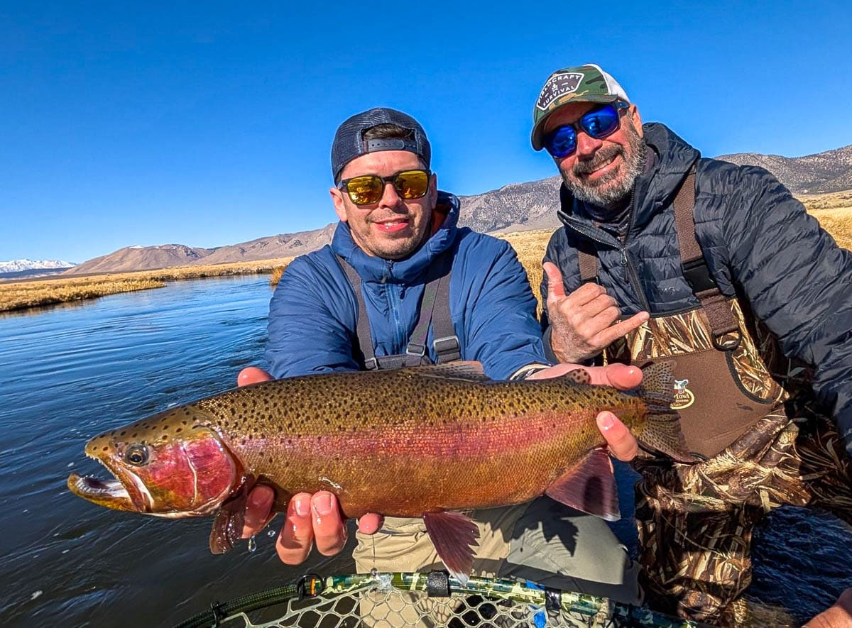 A pair of smiling fly fishermen holding a colorful large rainbow trout from the Upper Owens River near Mammoth Lakes, CA.