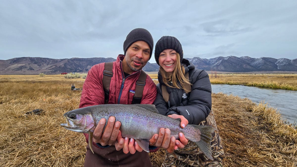 A smiling fly fisherman holding a larger rainbow trout on the Upper Owens River near Mammoth Lakes, CA.