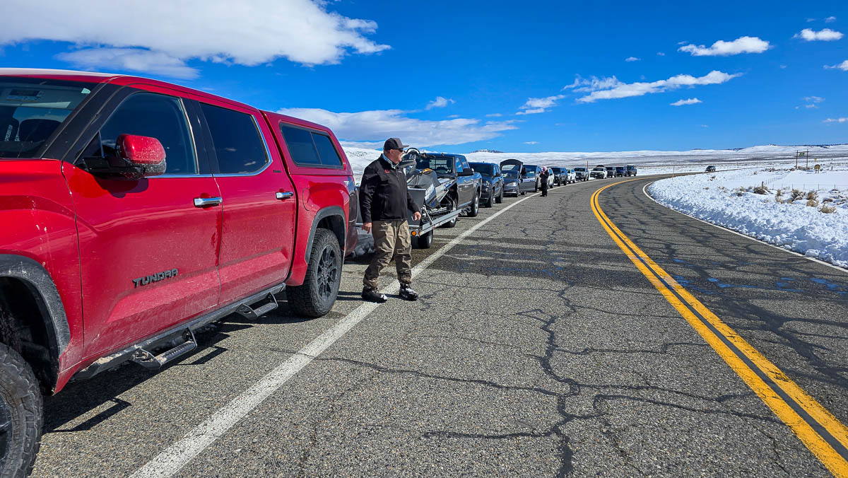 A bunch of cars and trucks parked on the side of the road near the Upper Owens River.