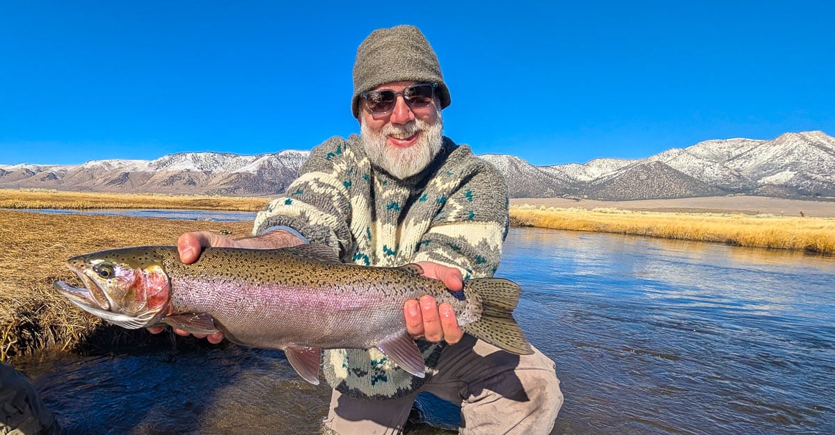 A pair of smiling fly fishermen holding a giant rainbow trout on the Upper Owens River near Mammoth Lakes, CA