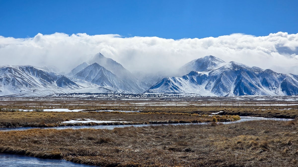 Snow covered mountains with a river in the foreground at the Upper Owens River near Mammoth Lakes, CA