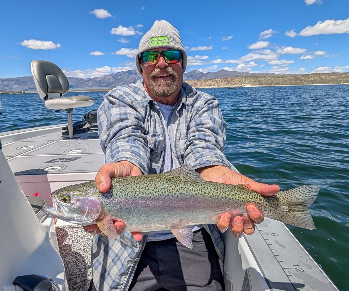 A fly fisherman holding a large rainbow trout on Crowley Lake near Mammoth Lakes, CA