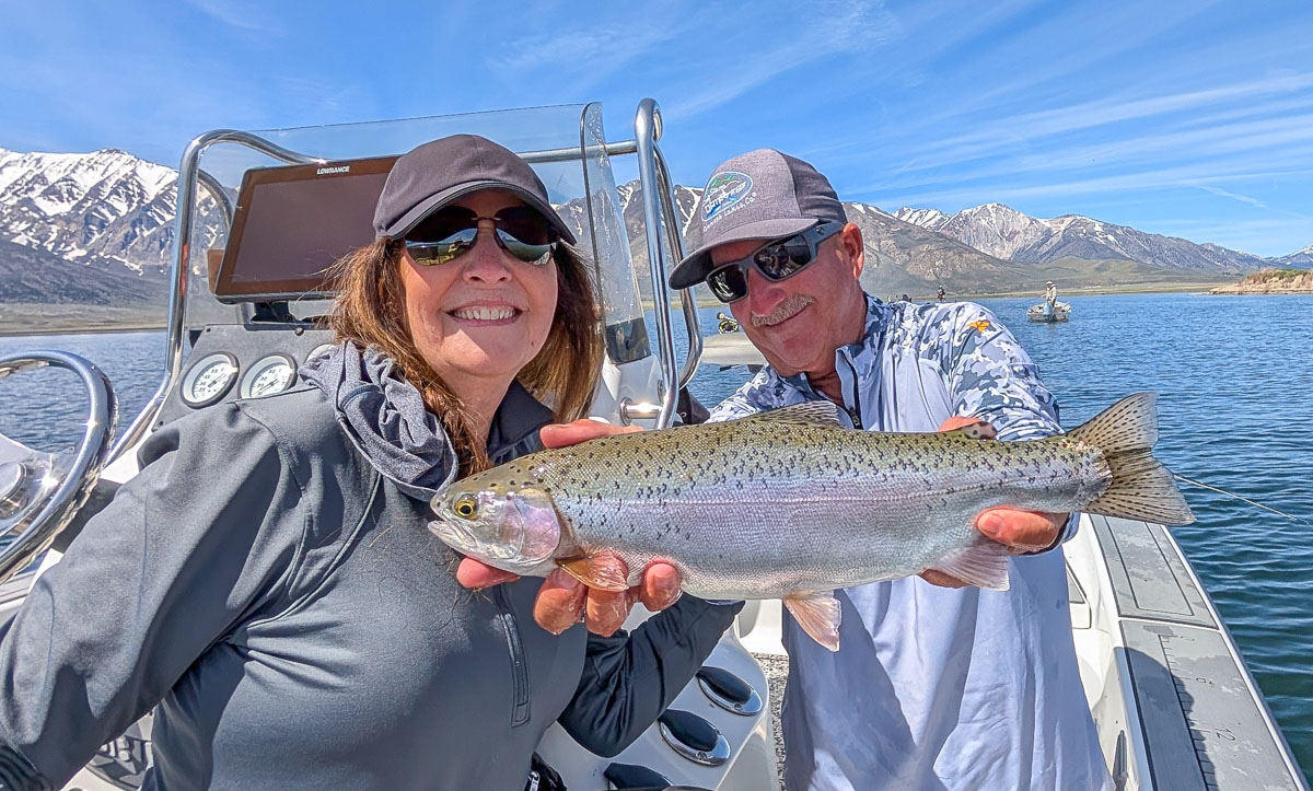 A fly fisherwoman holding a large rainbow trout on Crowley Lake near Mammoth Lakes, CA
