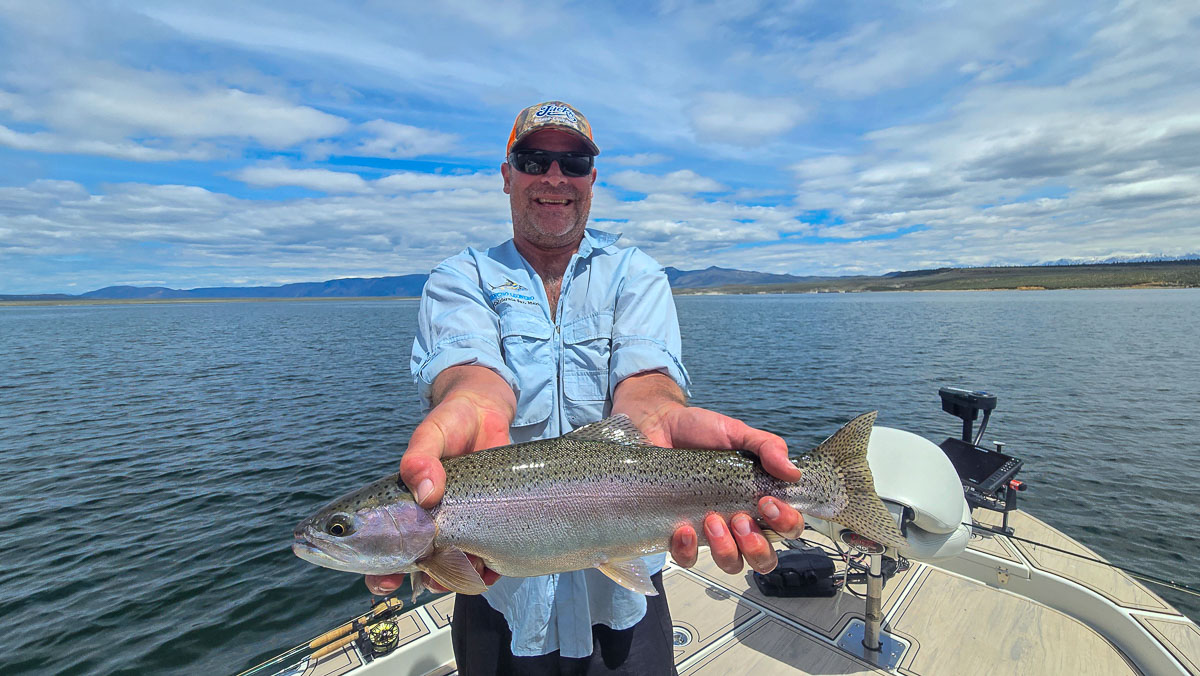 A fly fisherman holding a large rainbow trout on Crowley Lake near Mammoth Lakes, CA