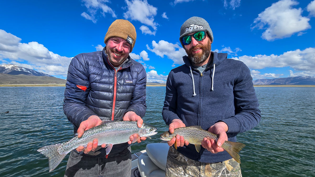 A pair of fly fishermen holding a rainbow and brown trout on Crowley Lake near Mammoth Lakes, CA.