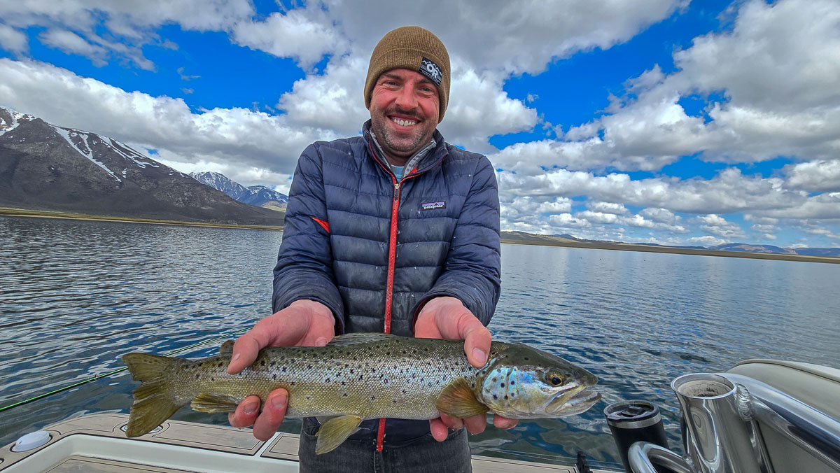 A fly fisherman holding a large brown trout on Crowley Lake near Mammoth Lakes, CA