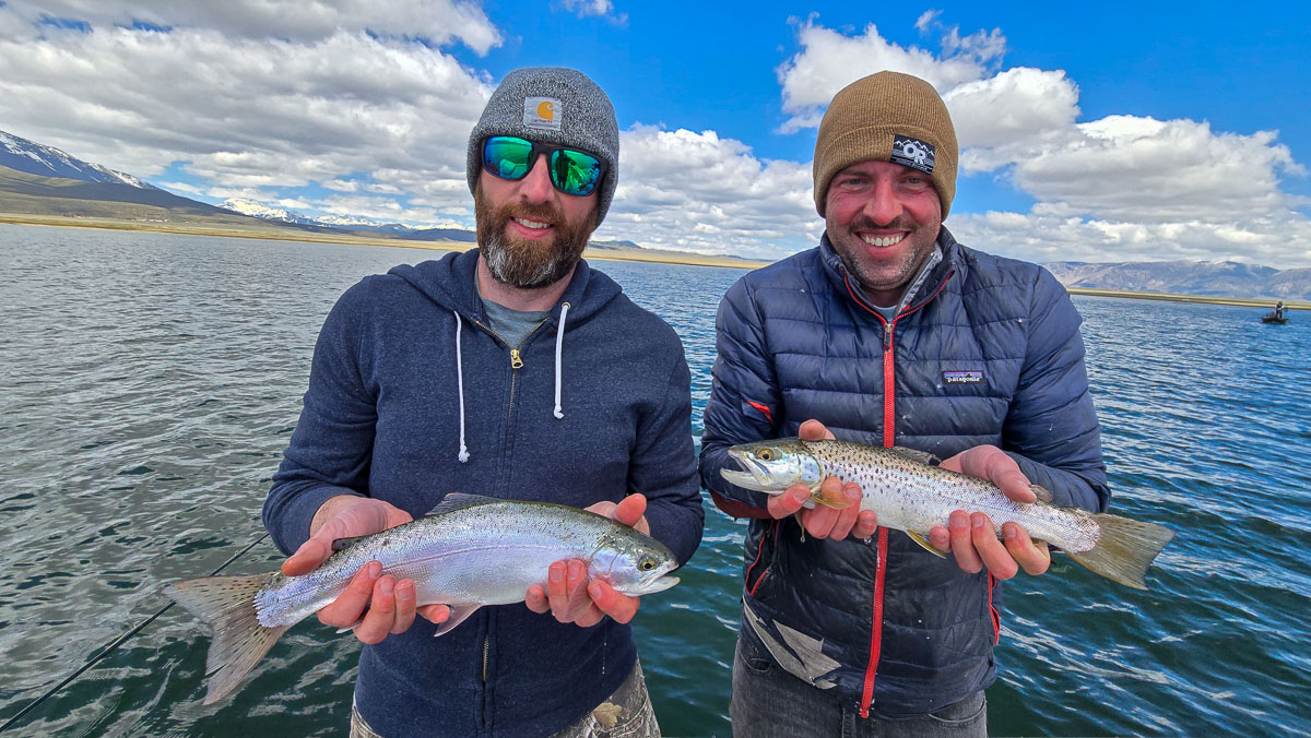 A pair of fly fishermen holding a rainbow and brown trout on Crowley Lake near Mammoth Lakes, CA.
