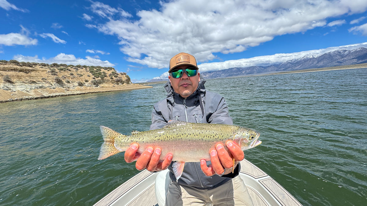 A fly fisherman holding a large rainbow trout on Crowley Lake near Mammoth Lakes, CA.