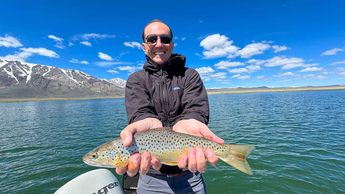 A fly fisherman holding a large brown trout on Crowley Lake near Mammoth Lakes, CA