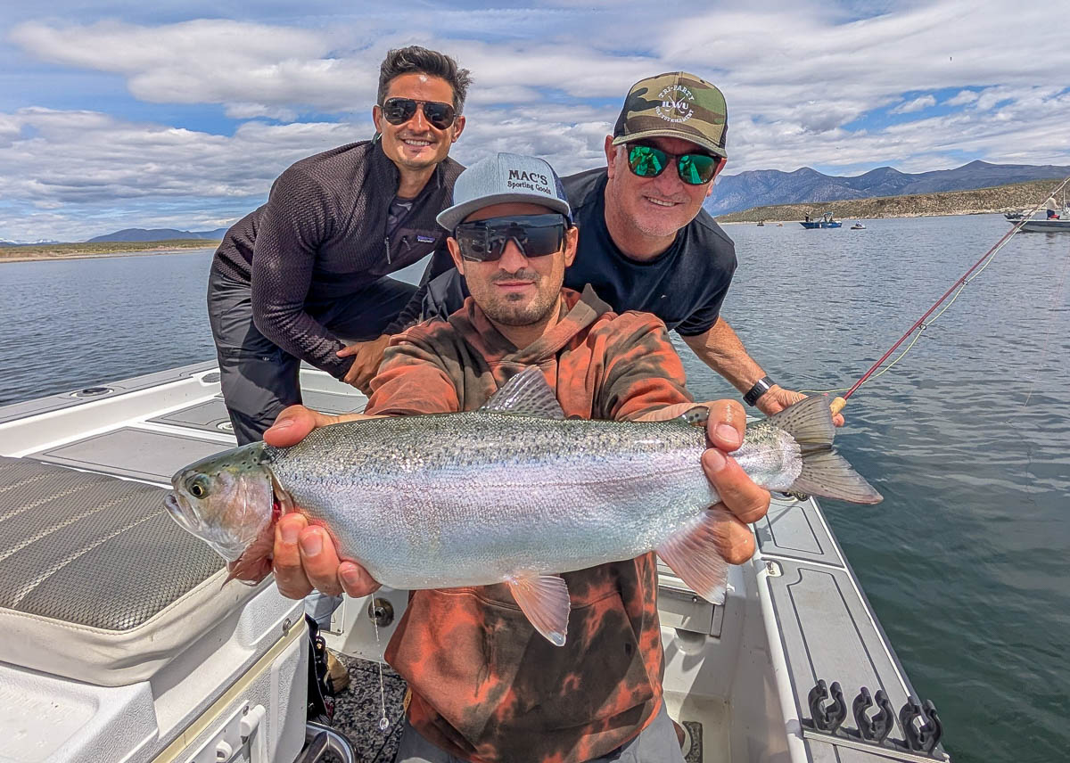 A trio of fly fishermen holding a rainbow and brown trout on Crowley Lake near Mammoth Lakes, CA.