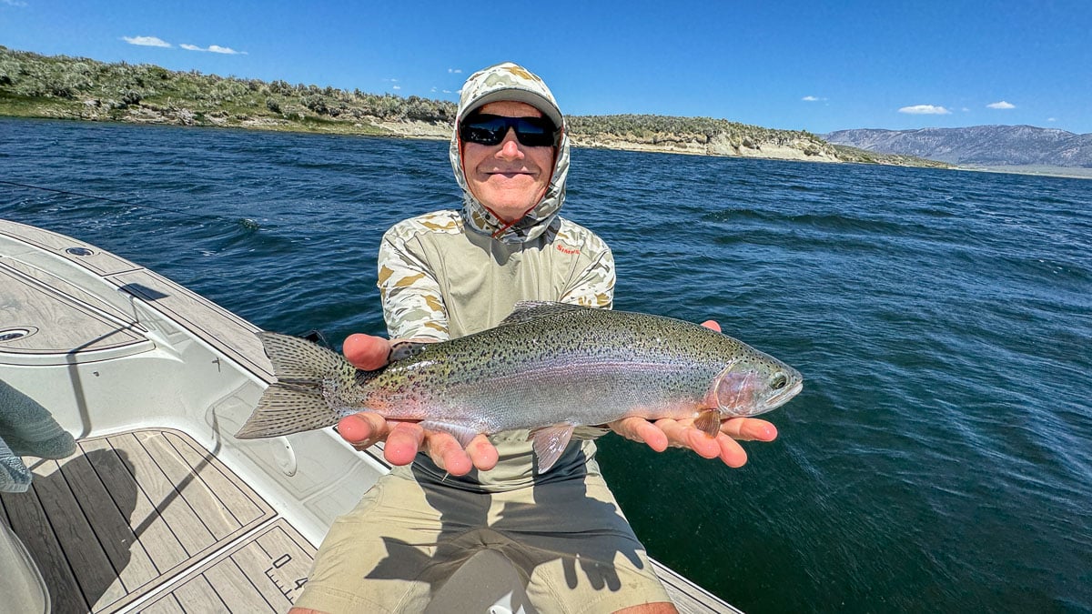 A fly fisherman holding a large rainbow trout on Crowley Lake near Mammoth Lakes, CA