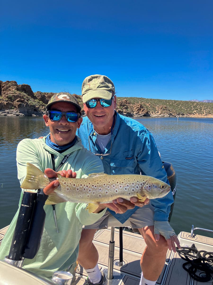 A fly fisherman holding a large brown trout on Crowley Lake near Mammoth Lakes, CA