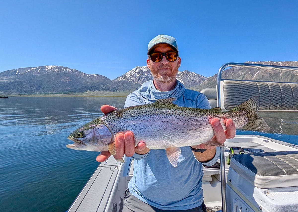 A fly fisherman holding a large rainbow trout on Crowley Lake near Mammoth Lakes, CA