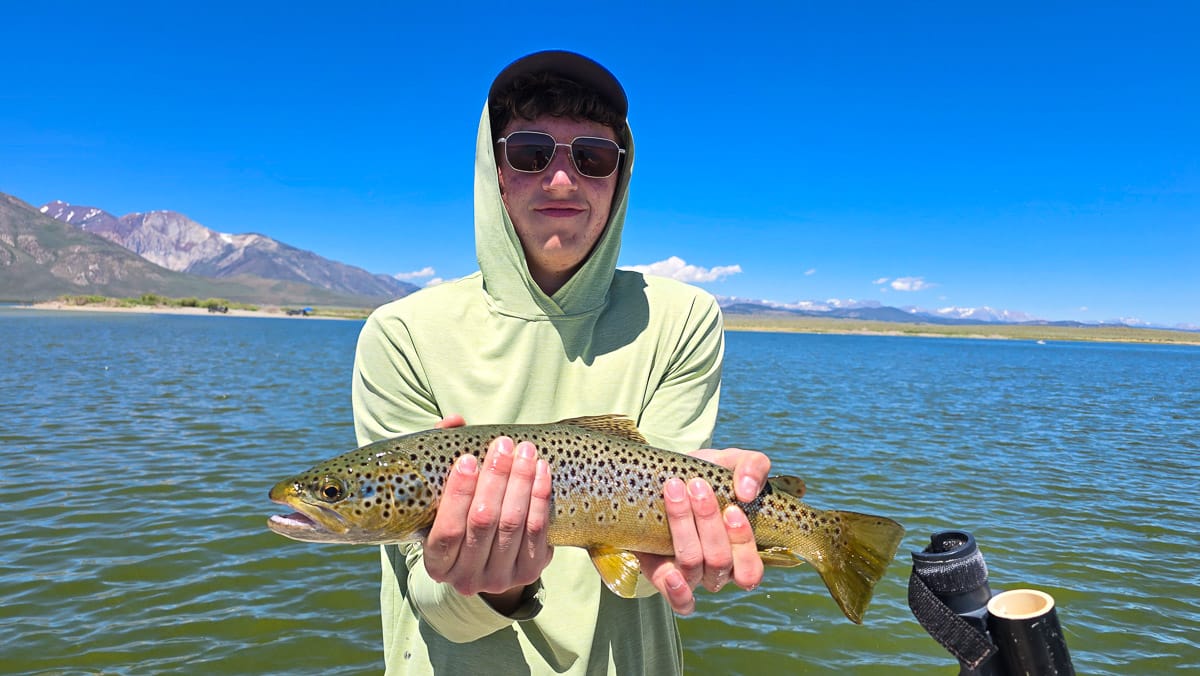A fly fisherman holding a large brown trout on Crowley Lake near Mammoth Lakes, CA