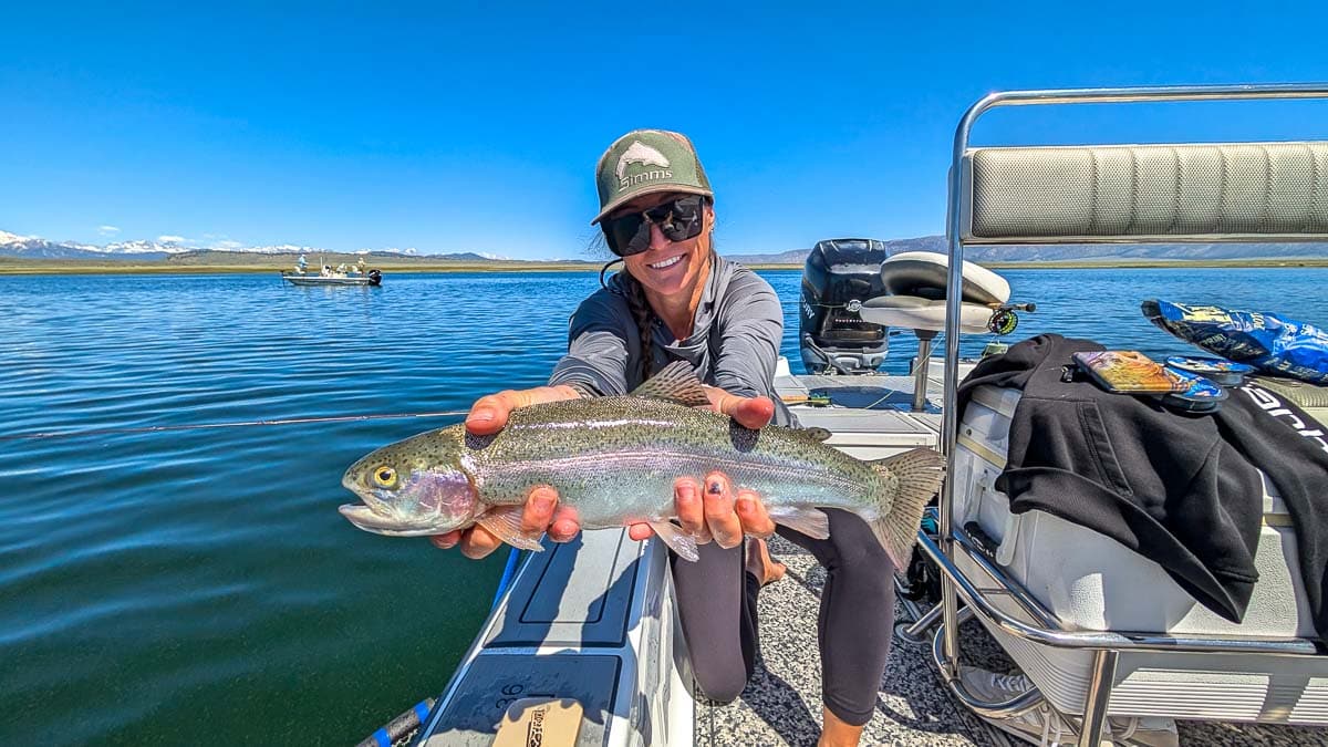 A fly fisherman holding a large rainbow trout on Crowley Lake near Mammoth Lakes, CA