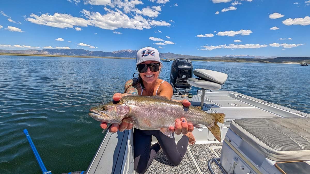 A fly fisherwoman holding a large cutthroat trout on Crowley Lake near Mammoth Lakes, CA