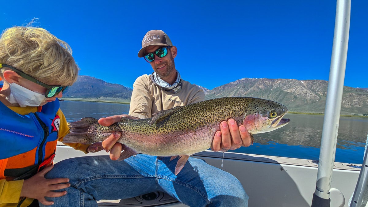 A fly fisherwoman holding a large rainbow trout on Crowley Lake near Mammoth Lakes, CA