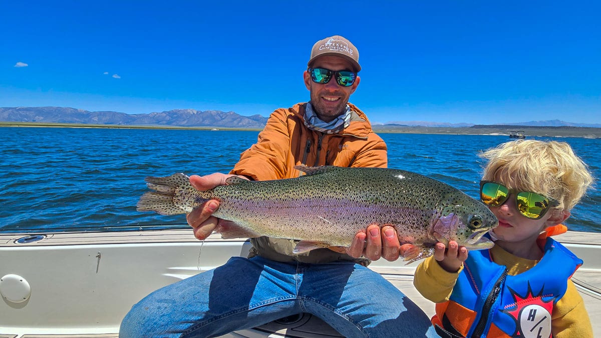 A fly fisherman holding a large rainbow trout on Crowley Lake near Mammoth Lakes, CA