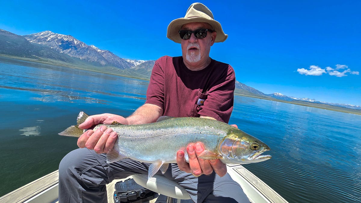 A fly fisherman holding a large cutthroat trout on Crowley Lake near Mammoth Lakes, CA