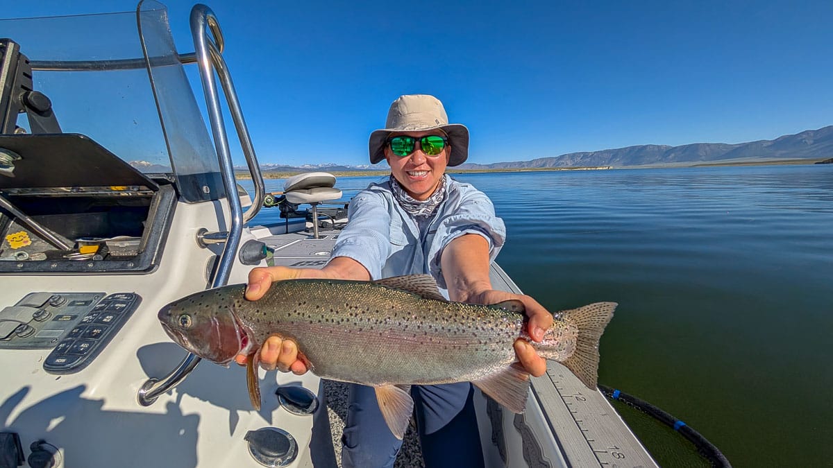 A fly fisherman holding a large rainbow trout on Crowley Lake near Mammoth Lakes, CA