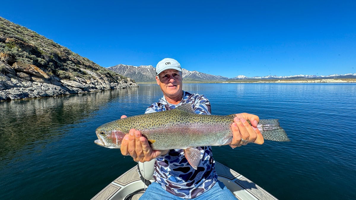 A fly fisherman holding a large rainbow trout on Crowley Lake near Mammoth Lakes, CA