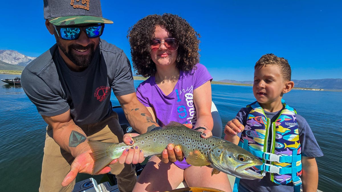 A fly fisherwoman holding a large rainbow trout on Crowley Lake near Mammoth Lakes, CA