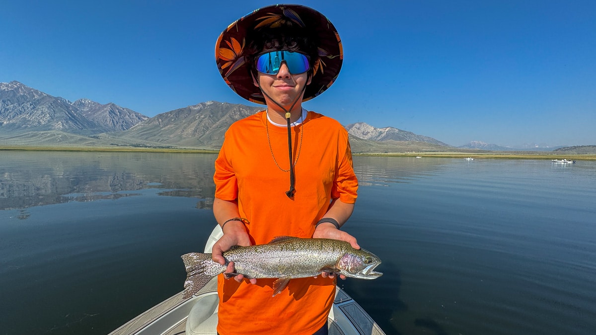 A fly fisherman holding a large brown trout on Crowley Lake near Mammoth Lakes, CA