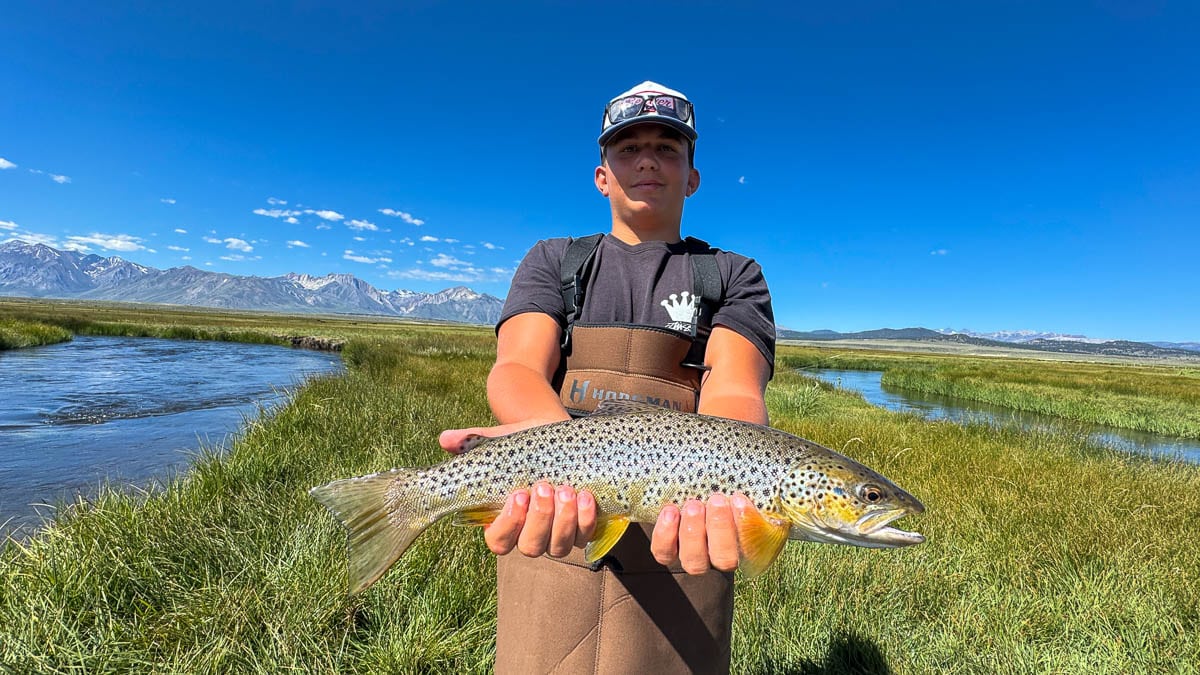 A fly fisherman holding a large brown trout on Crowley Lake near Mammoth Lakes, CA