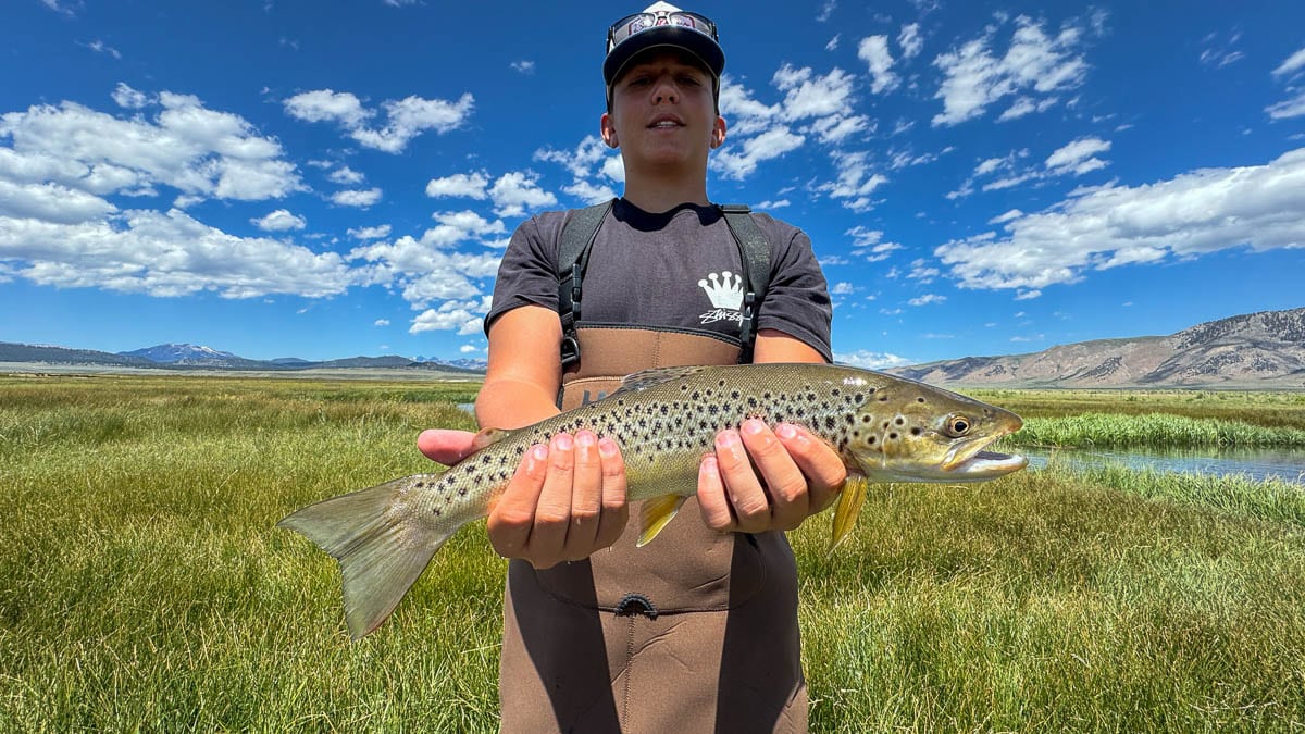 A fly fisherman holding a large brown trout on Crowley Lake near Mammoth Lakes, CA