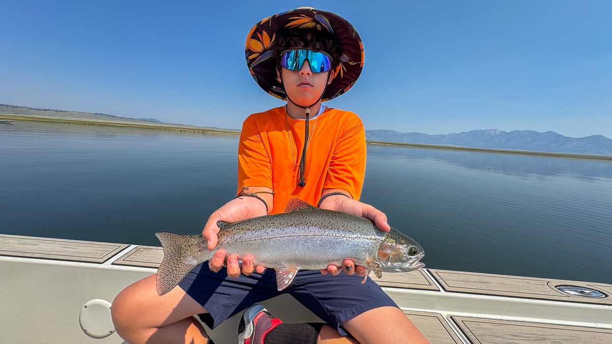A fly fisherman holding a large cutthroat trout on Crowley Lake near Mammoth Lakes, CA
