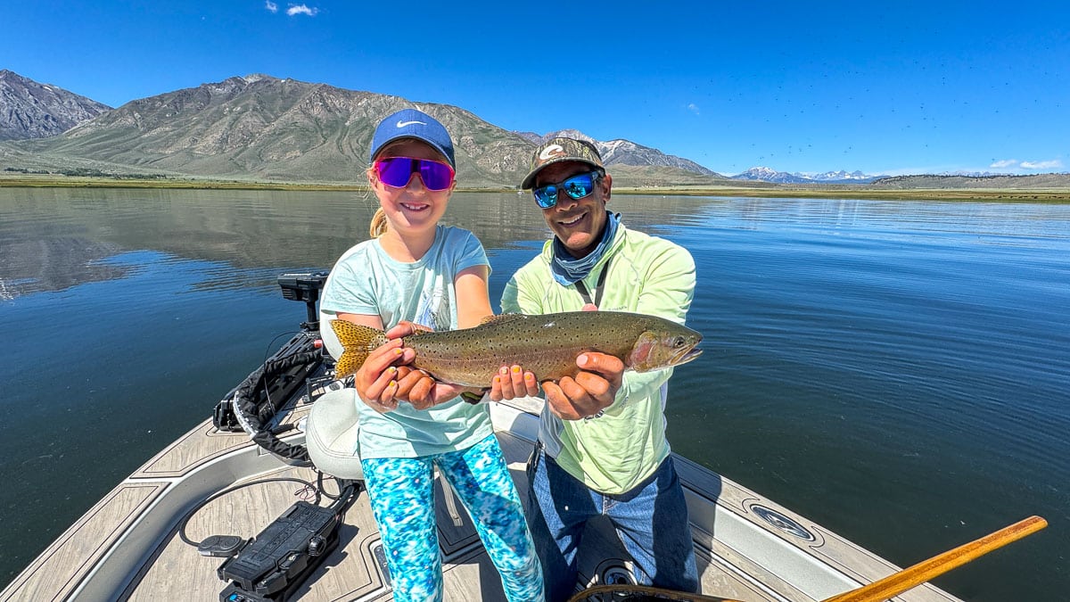 A fly fisherman holding a large rainbow trout on Crowley Lake near Mammoth Lakes, CA
