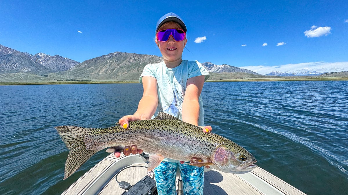 A fly fisherman holding a large cutthroat trout on Crowley Lake near Mammoth Lakes, CA