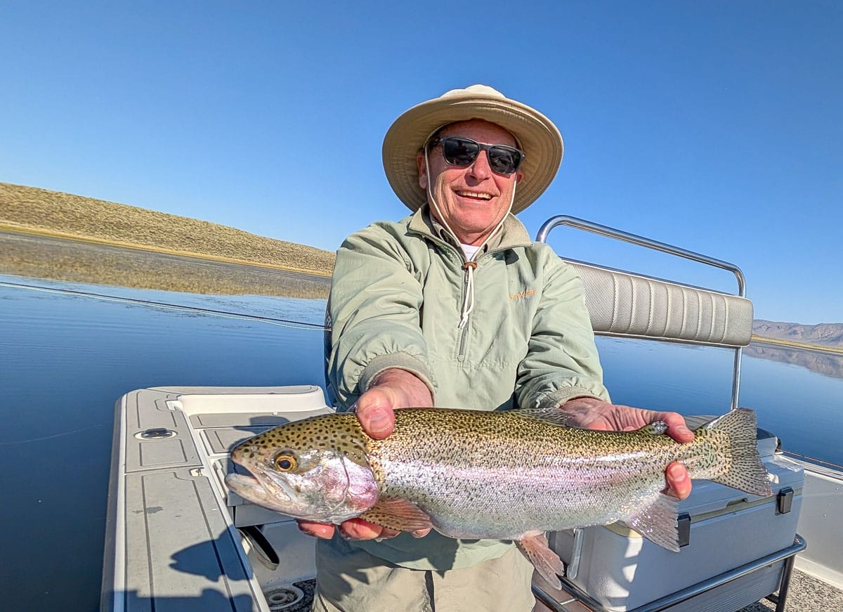 A female fly fisherman holding a large brown trout on Crowley Lake near Mammoth Lakes, CA