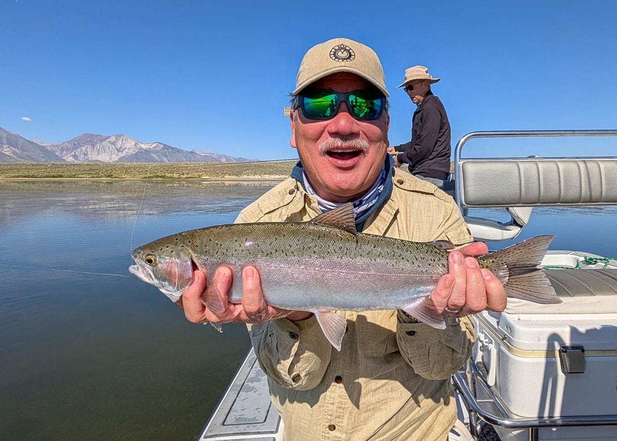 A fly fisherman holding a large brown trout on Crowley Lake near Mammoth Lakes, CA