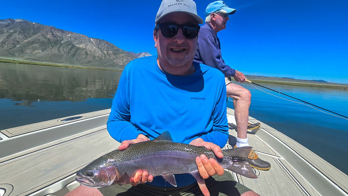 A fly fisherman holding a large brown trout on Crowley Lake near Mammoth Lakes, CA