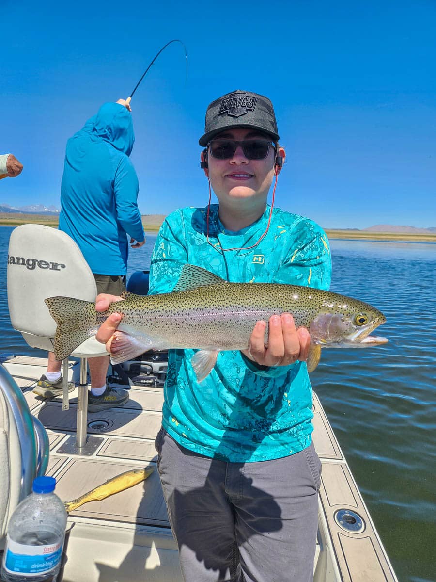 A fly fisherman holding a large rainbow trout on Crowley Lake near Mammoth Lakes, CA