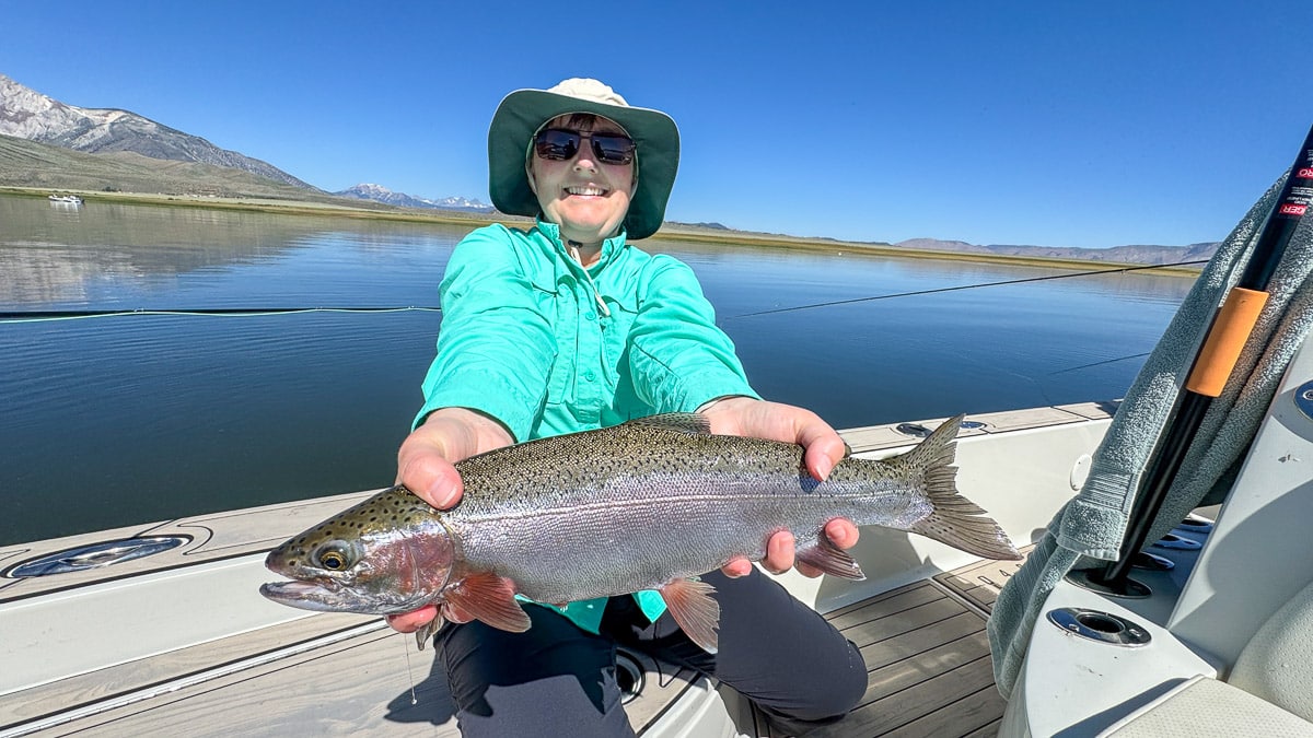 A fly fisherman holding a large brown trout on Crowley Lake near Mammoth Lakes, CA