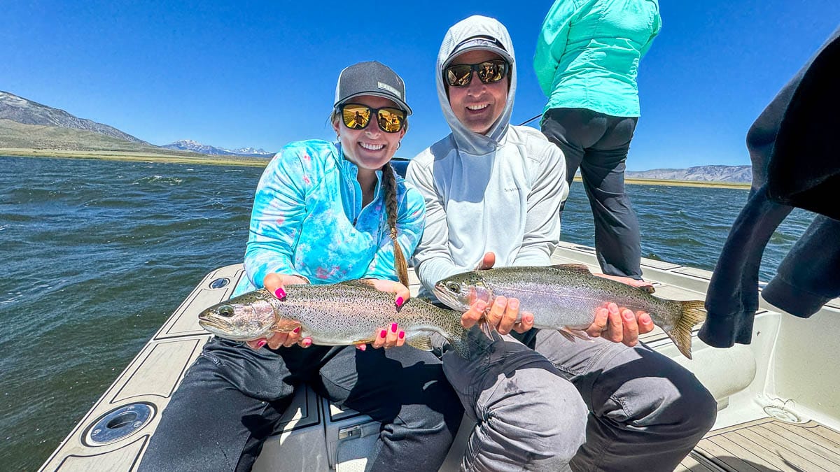 A fly fisherman holding a large rainbow trout on Crowley Lake near Mammoth Lakes, CA