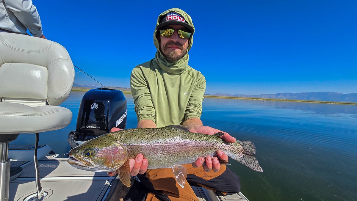 A fly fisherman holding a large brown trout on Crowley Lake near Mammoth Lakes, CA