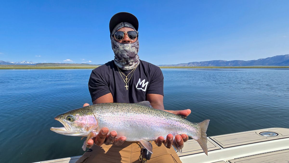 A fly fisherman holding a large brown trout on Crowley Lake near Mammoth Lakes, CA
