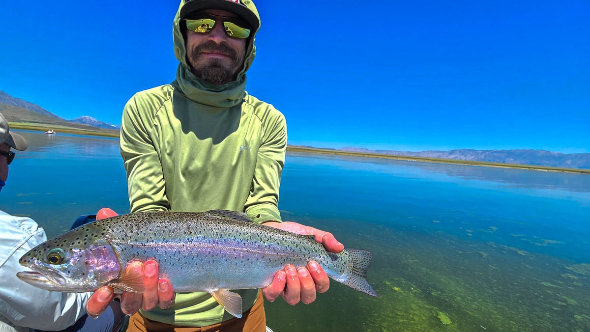 A fly fisherwoman holding a large rainbow trout on Crowley Lake near Mammoth Lakes, CA