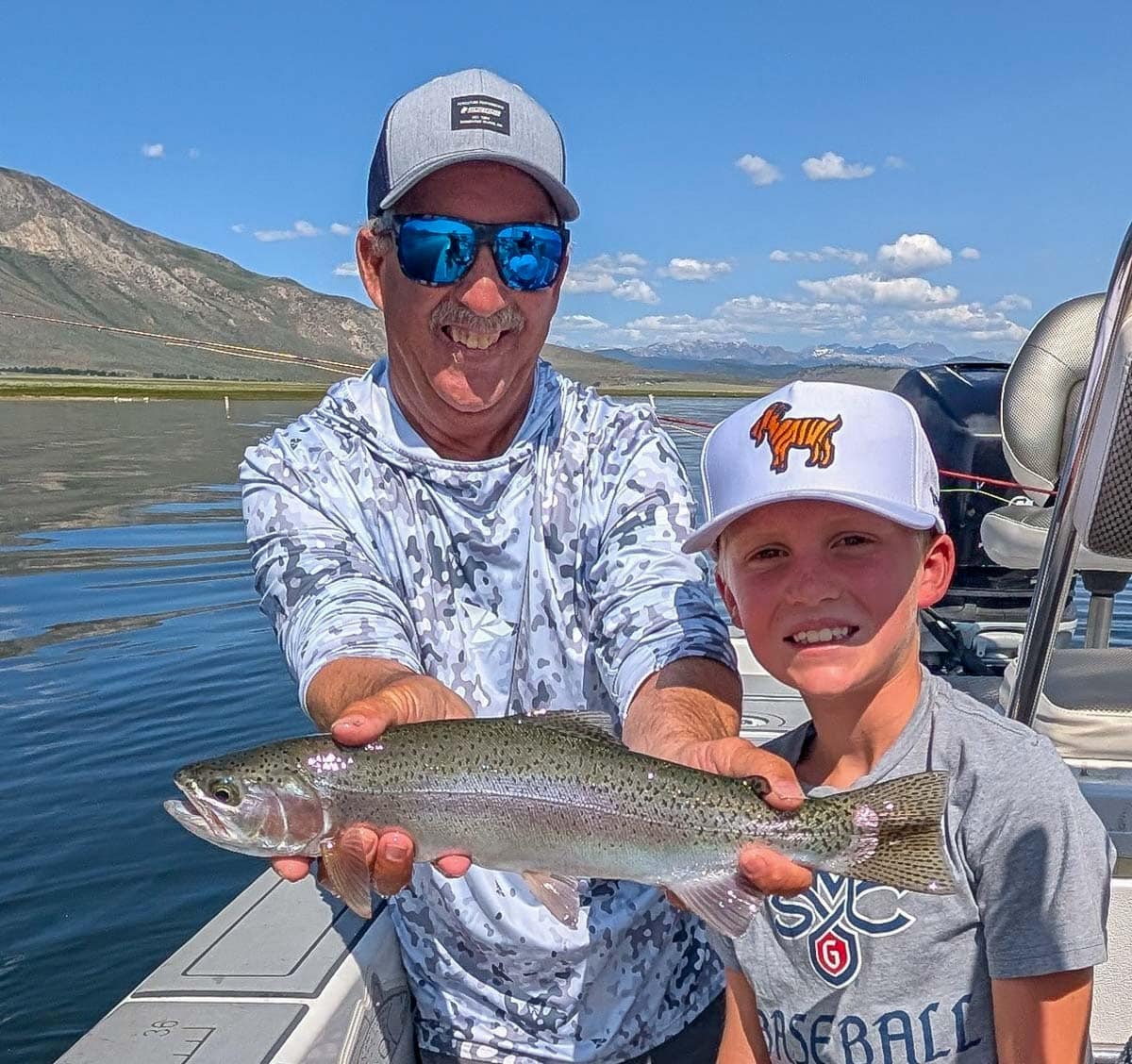 A fly fisherman holding a large rainbow trout on Crowley Lake near Mammoth Lakes, CA