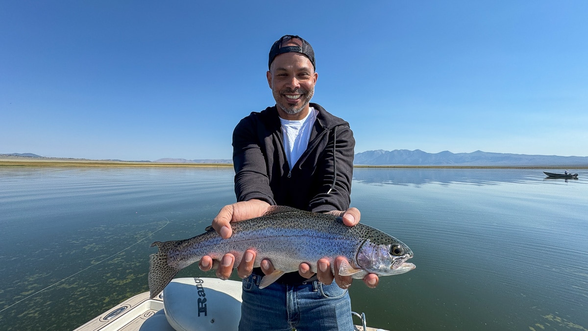 A smiling fly fisherman holding a large brown trout on the Crowley Lake near Mammoth Lakes, CA.