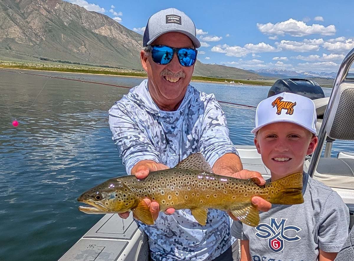A fly fisherwoman holding a large rainbow trout on Crowley Lake near Mammoth Lakes, CA