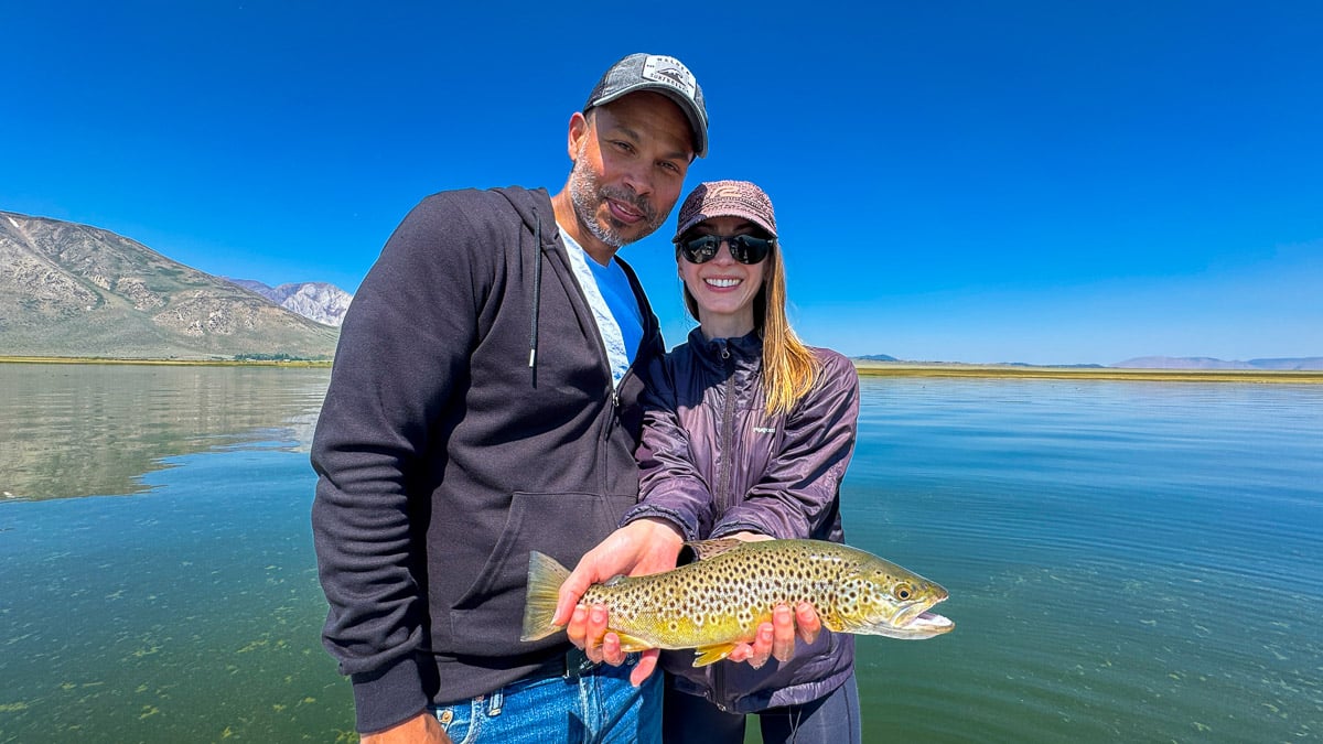 A fly fisherman holding a large rainbow trout on Crowley Lake near Mammoth Lakes, CA