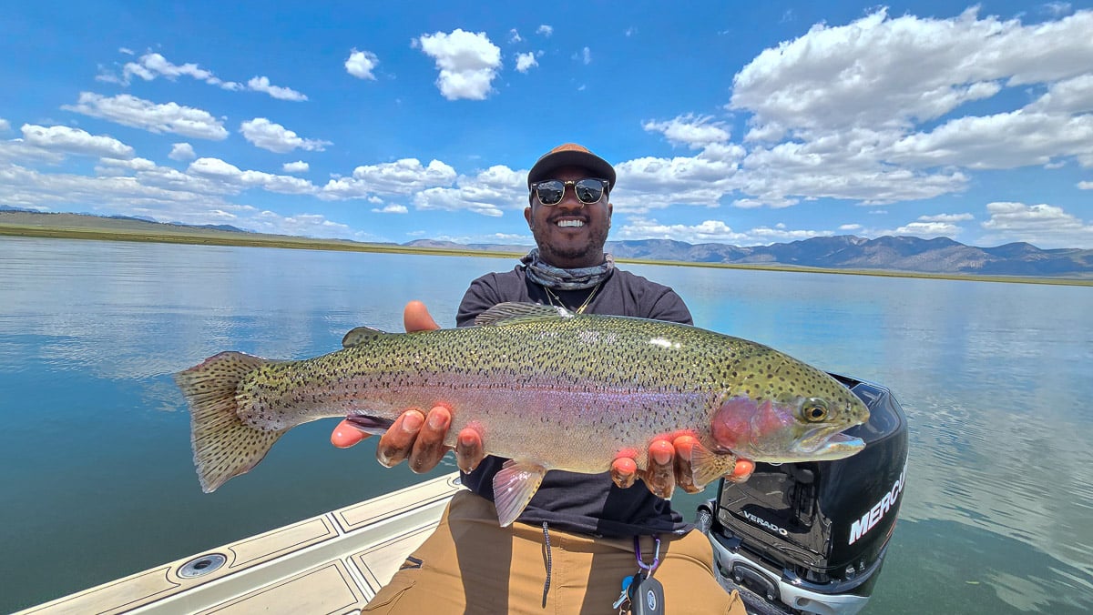 A fly fisherman holding a large brown trout on Crowley Lake near Mammoth Lakes, CA