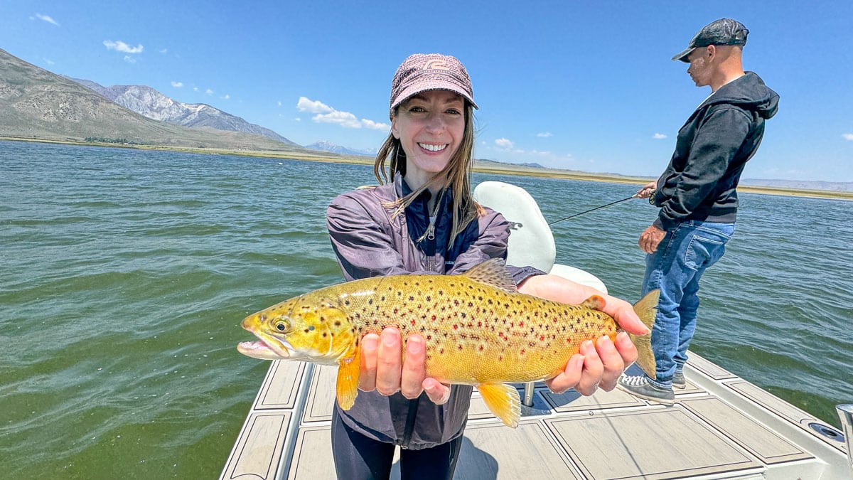 A fly fisherwoman holding a large rainbow trout on Crowley Lake near Mammoth Lakes, CA
