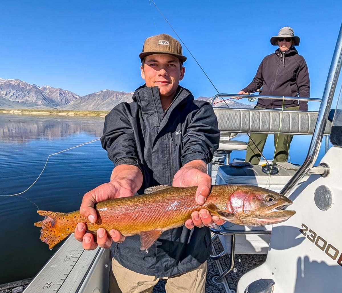A fly fisherman holding a large brown trout on Crowley Lake near Mammoth Lakes, CA