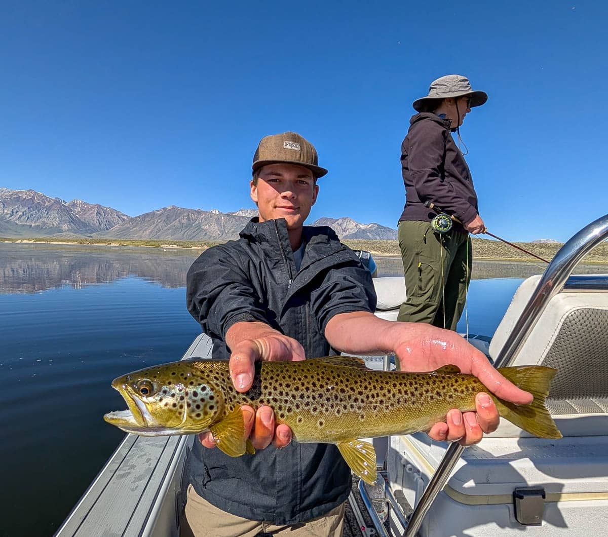 A fly fisherman holding a large brown trout on Crowley Lake near Mammoth Lakes, CA